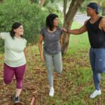 Three adults stretching before a run, illustrating research on uric acid and exercise training