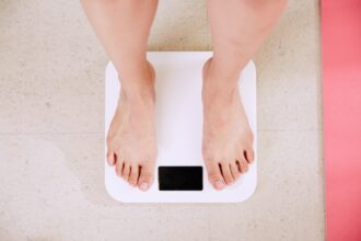 Person standing on a digital scale, illustrating body weight and body fat estimation