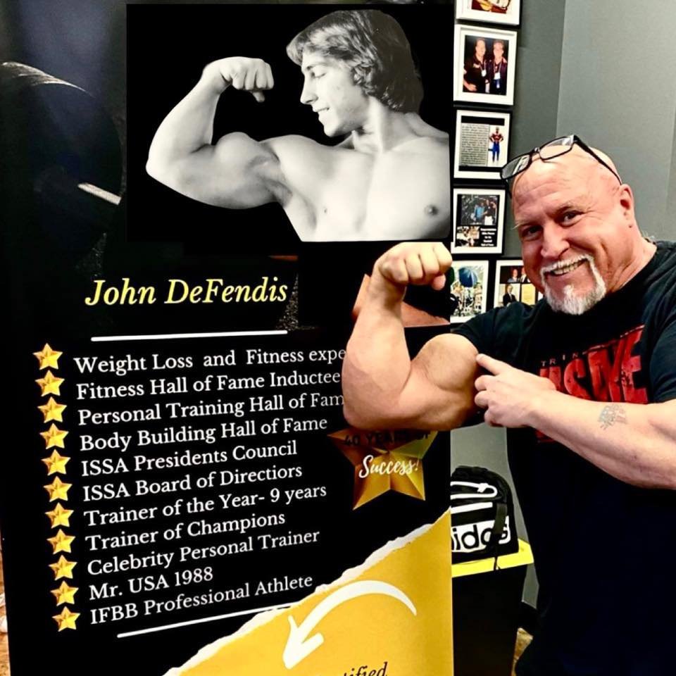 John DeFendis beside a display featuring a photograph from his early bodybuilding career