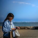Woman checking a smartwatch during an outdoor walk, illustrating adaptive exercise prompts and wearable activity tracking