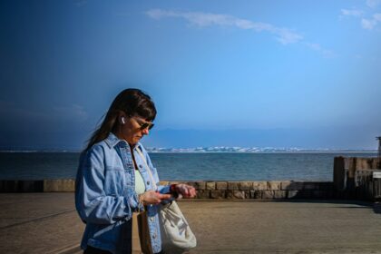Woman checking a smartwatch during an outdoor walk, illustrating adaptive exercise prompts and wearable activity tracking