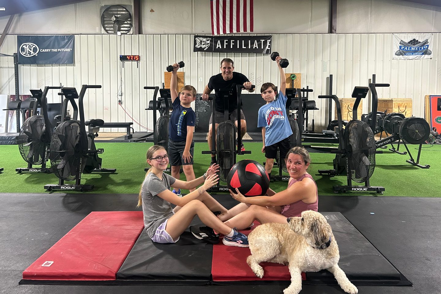 A family training together at Lodestar Fitness with the gym dog nearby