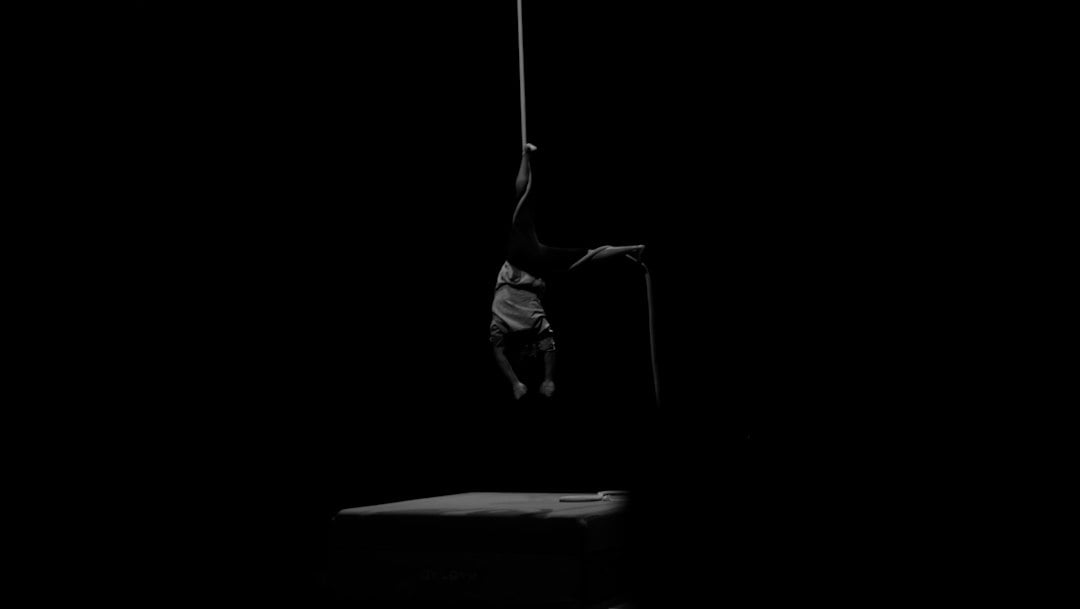 A practitioner gripping a vertical bar during pole dance practice, a hanging position that loads the shoulder rotators