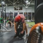 Man squatting in a strength gym, illustrating rest intervals during resistance exercise