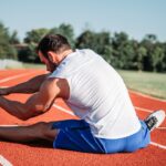 Runner stretching calf after training, illustrating exercise-associated muscle cramps