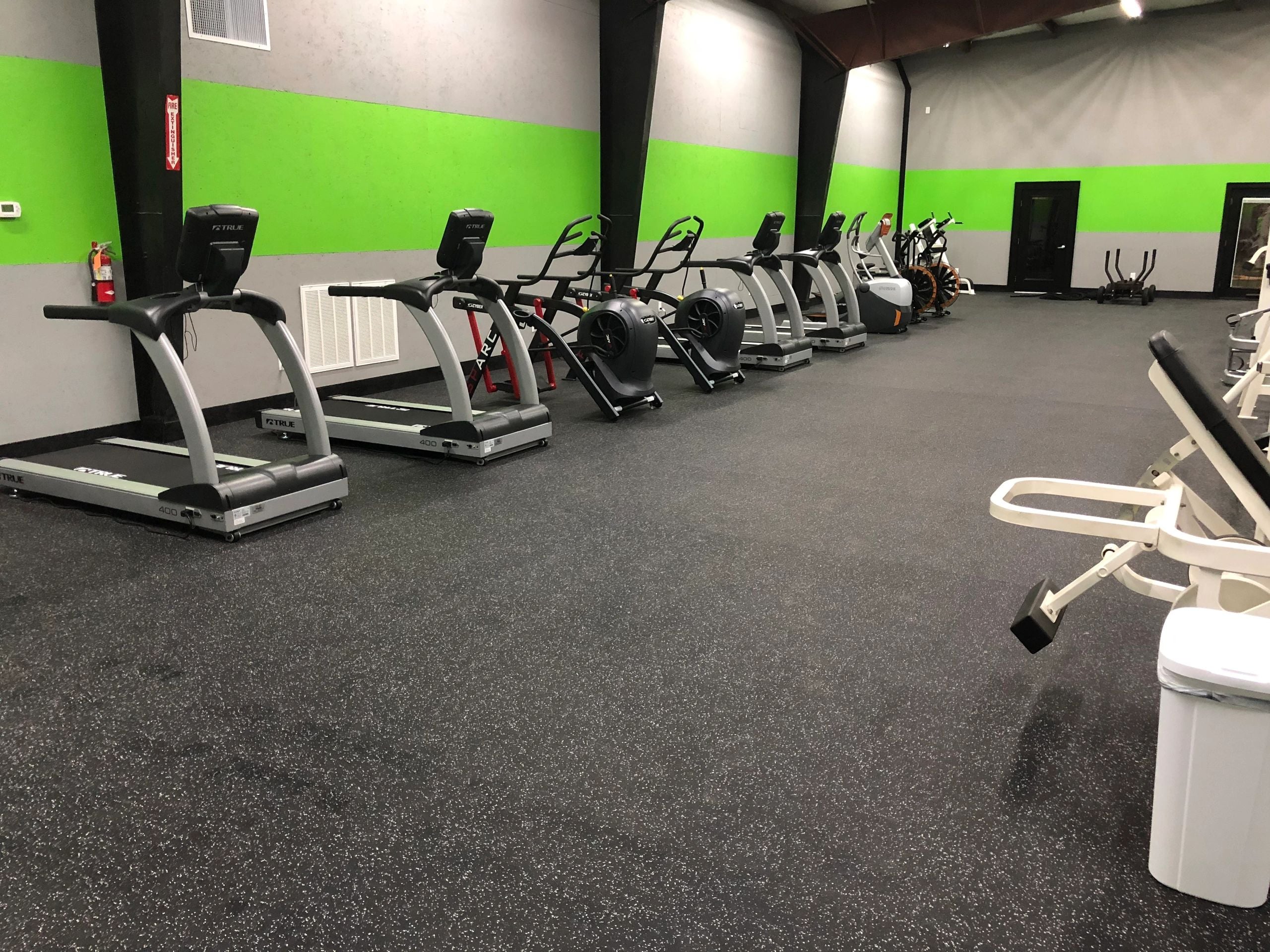Cardio equipment along the green and gray wall at Stars Sports and Fitness