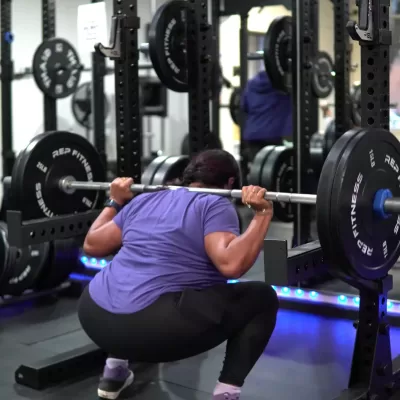 A woman practicing a barbell squat at The Lifting Legacy