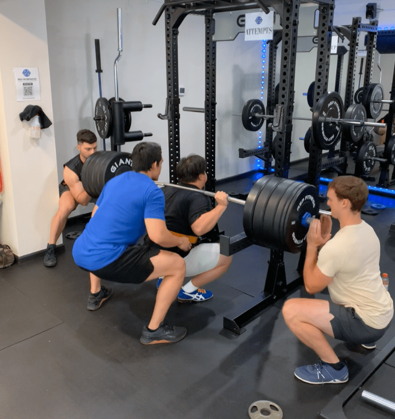 A lifter squatting with spotters at The Lifting Legacy in Seattle