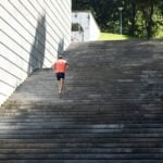 Man running up outdoor stone steps, illustrating vigorous activity and lower mortality risk