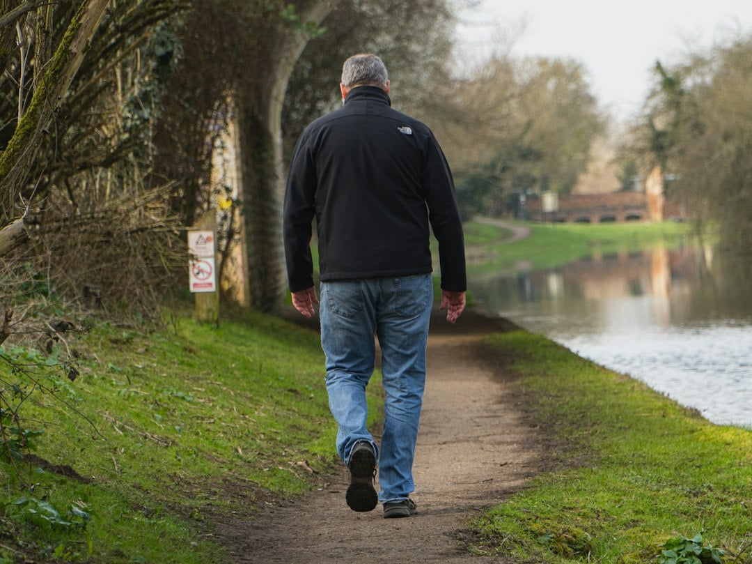 A man walking a riverside path, the kind of moderate activity measured in research on genetic risk and diabetes