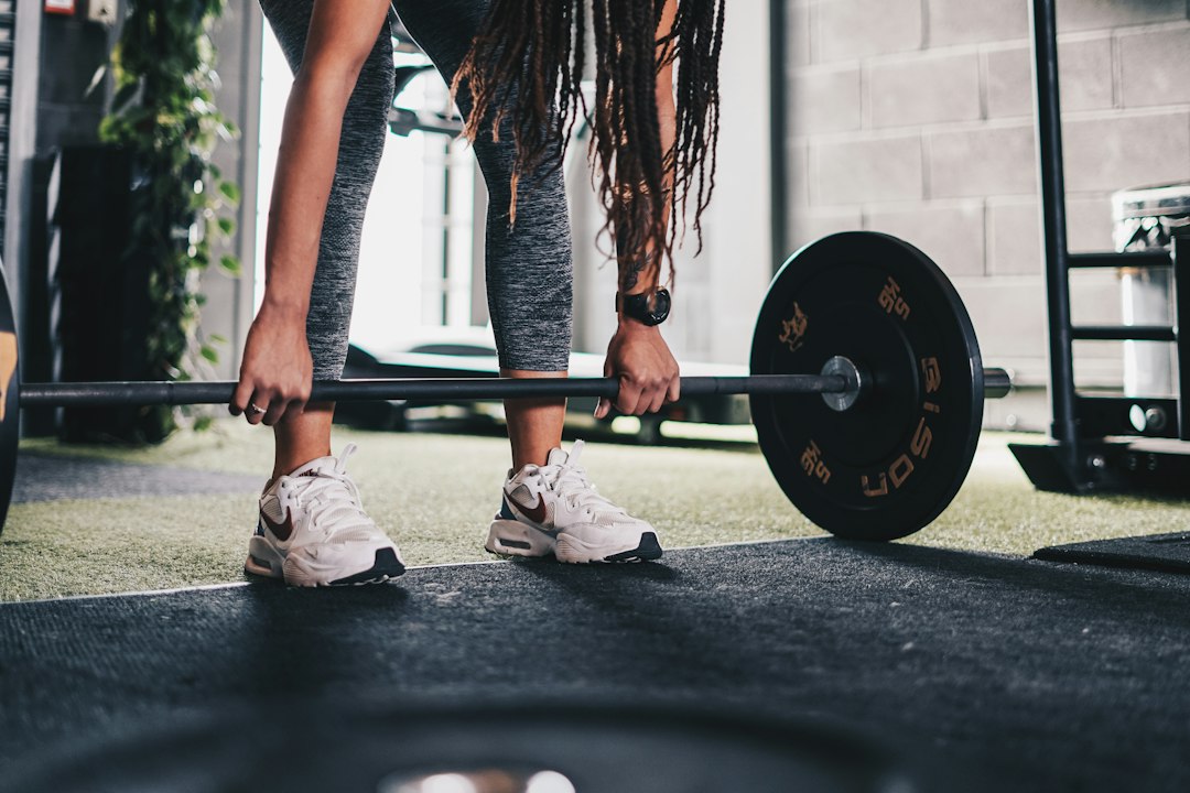 Woman lifting a barbell in a gym, weight-bearing training of the kind reviewed for bone health