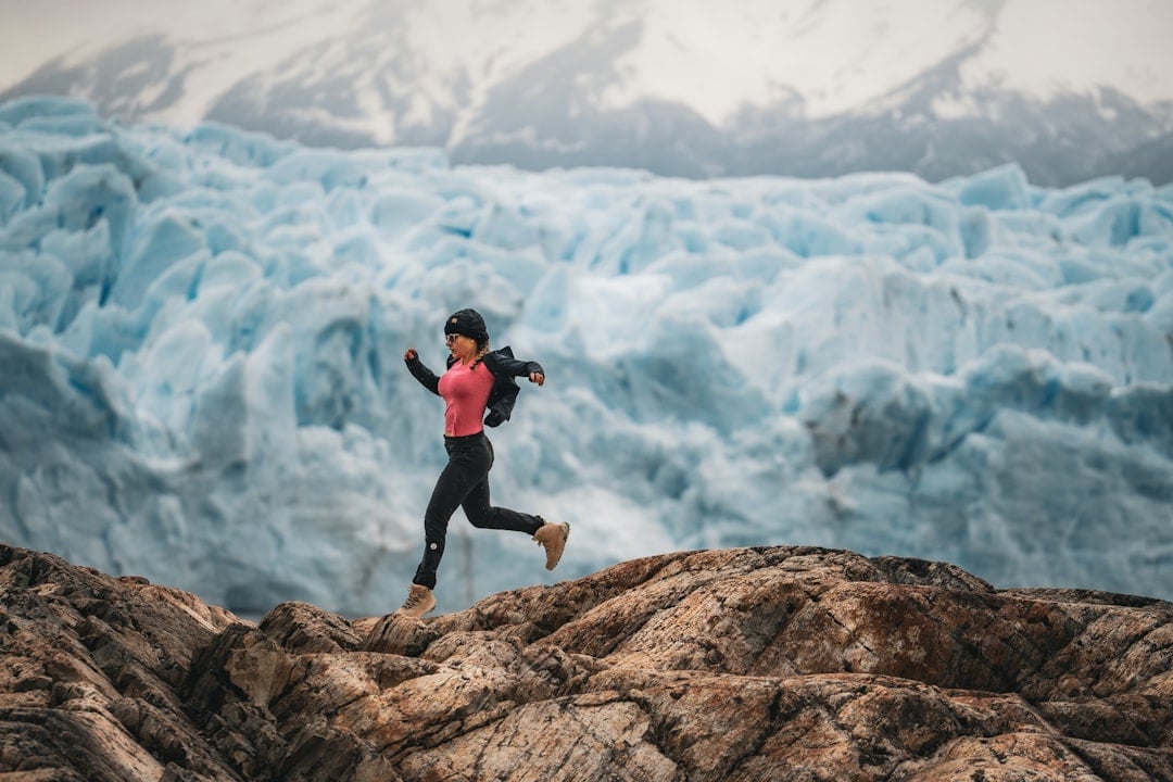 Woman running on rocks near a glacier, a high-altitude setting linked to hypoxic training