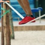 Adult balancing barefoot on webbing outdoors during a slackline training session