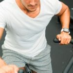 Adult cycling on a gym stationary bike, the kind of aerobic training linked to better endothelial function