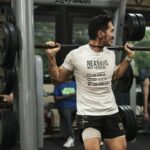 Athlete performing a barbell back squat during velocity-based training in a gym