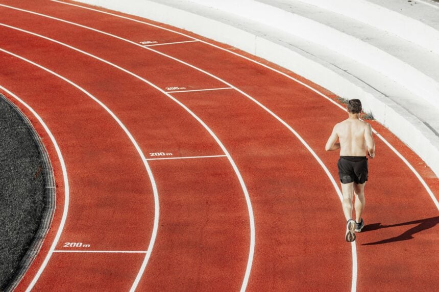 A distance runner on a track bend, where running performance is measured in collegiate athletes
