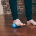Bare foot rolling a massage ball on the floor, illustrating flexible flatfoot exercise research