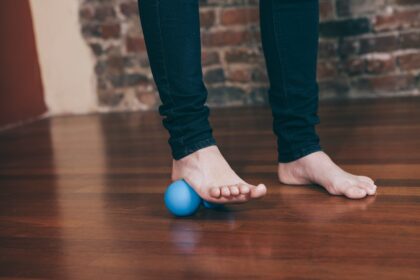 Bare foot rolling a massage ball on the floor, illustrating flexible flatfoot exercise research