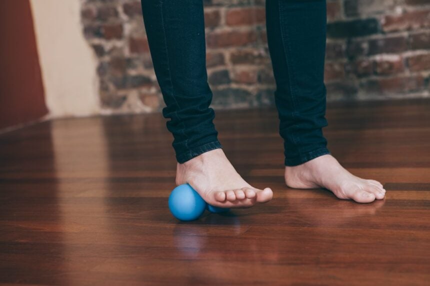 Bare foot rolling a massage ball on the floor, illustrating flexible flatfoot exercise research