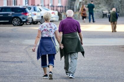 An older couple walking outdoors, the kind of habit linked with slower functional decline after age 50