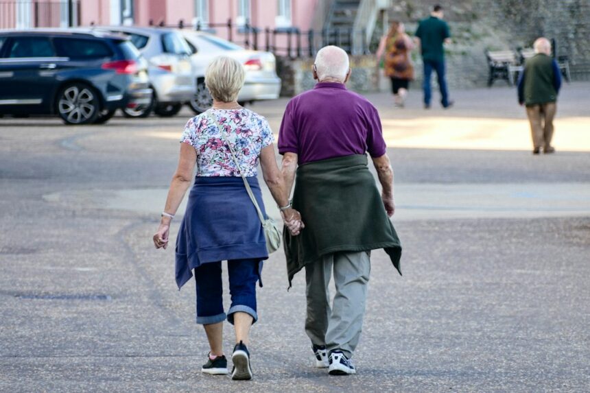 An older couple walking outdoors, the kind of habit linked with slower functional decline after age 50