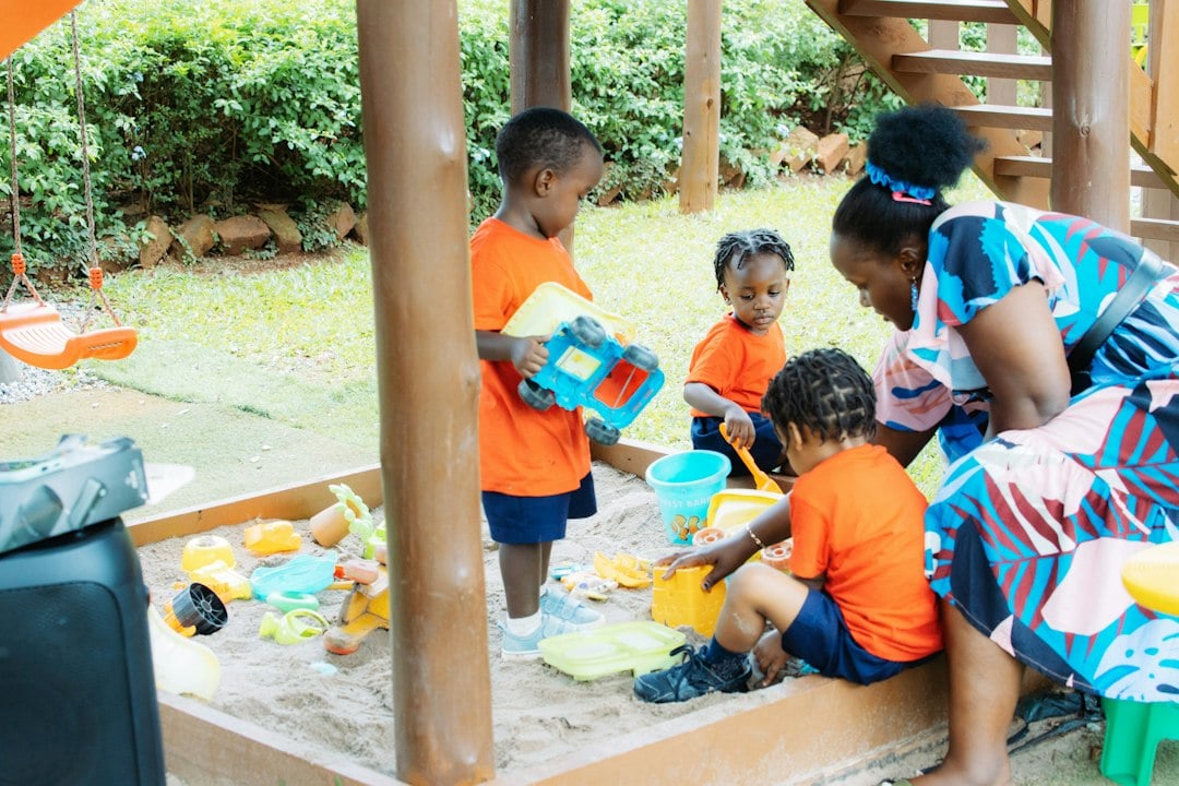 Preschool activity in a sandbox as a member of staff supervises the children