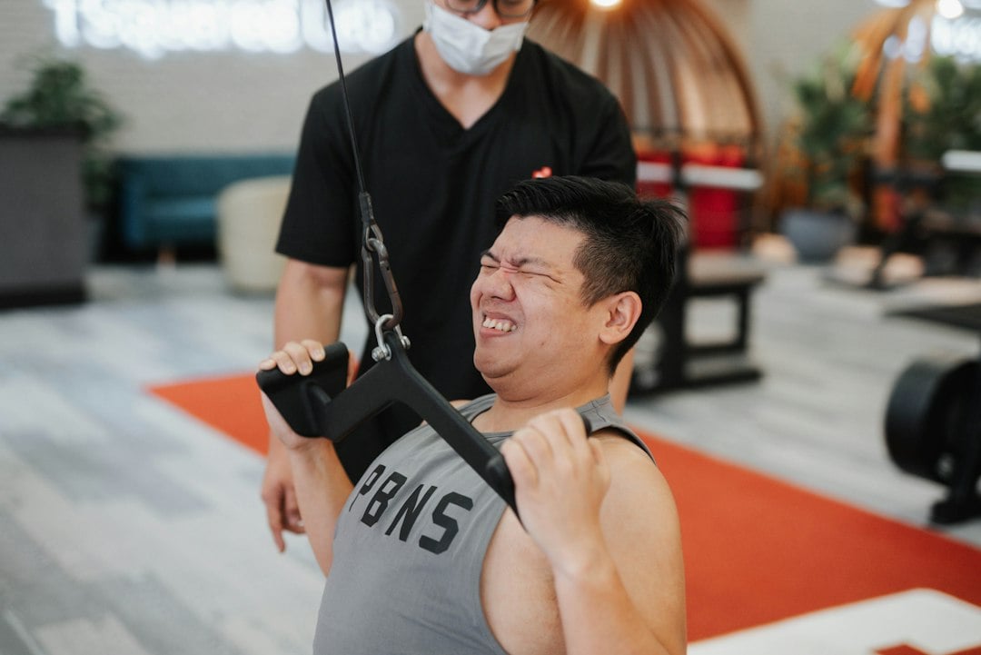 A trainer coaching a client through a strength exercise, the supervised format common in musculoskeletal pain research