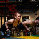 Two athletes holding a push-up position on a gym floor during core training