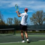 Tennis player striking the ball in a trial measuring serve accuracy under rising fatigue