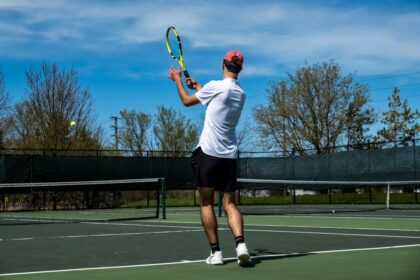 Tennis player striking the ball in a trial measuring serve accuracy under rising fatigue