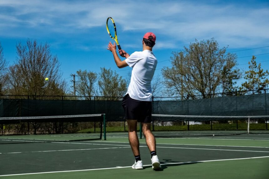 Tennis player striking the ball in a trial measuring serve accuracy under rising fatigue