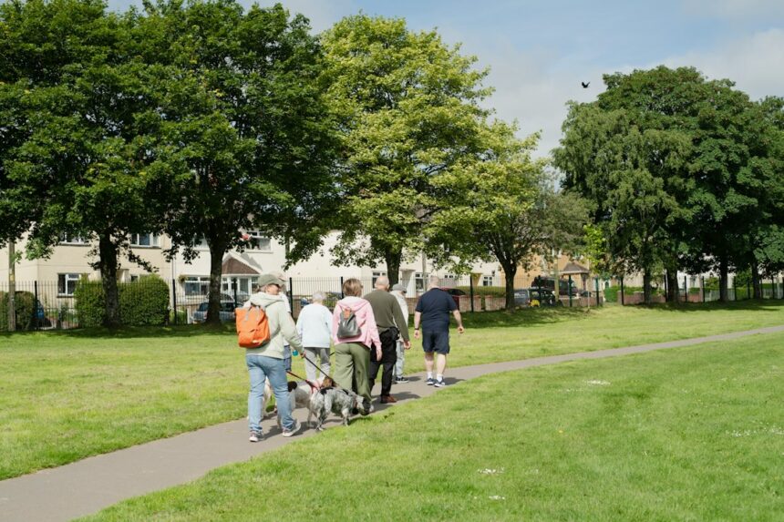 Adults walking together along a sunny park path, the kind of weekly activity studied for Parkinson disease progression