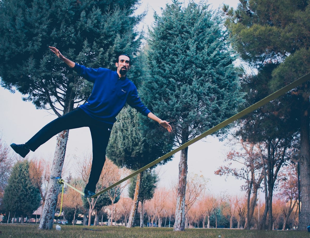Woman balancing on a low line strapped between trees, the setup used for slackline training