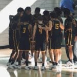 Youth basketball team huddled on the court before starting a warm-up program